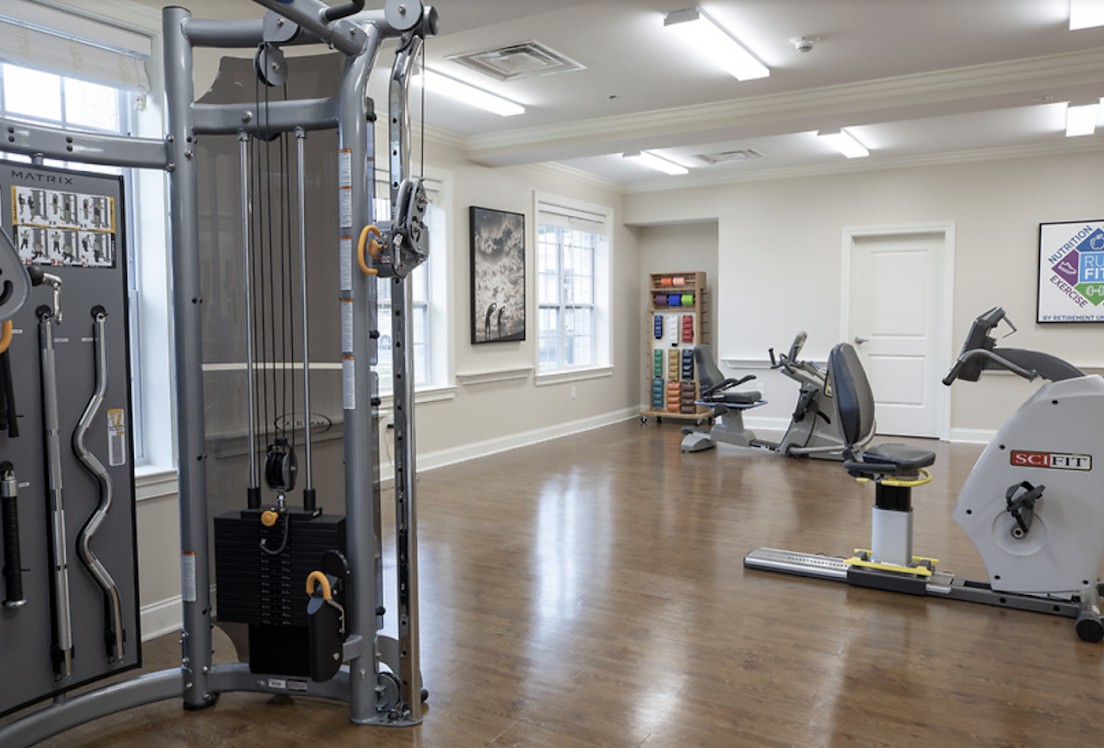 A clean and spacious gym with various exercise machines and fitness equipment.