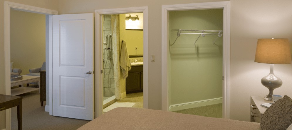 A modern bedroom with an open view of the bathroom and closet.