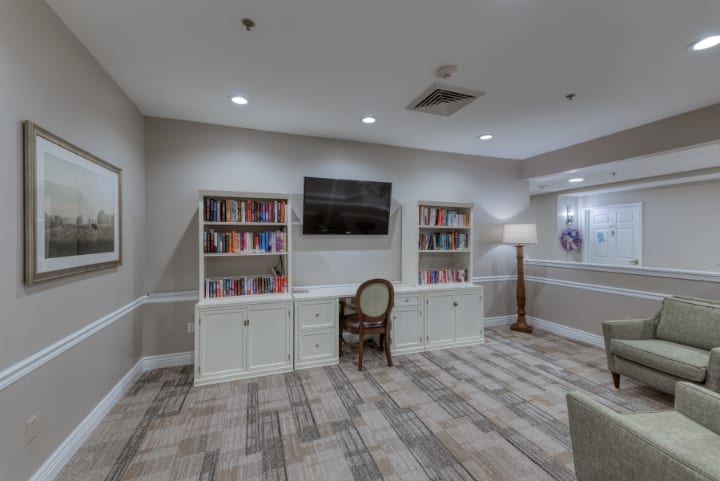 A cozy library room with bookshelves, a chair, and a television.