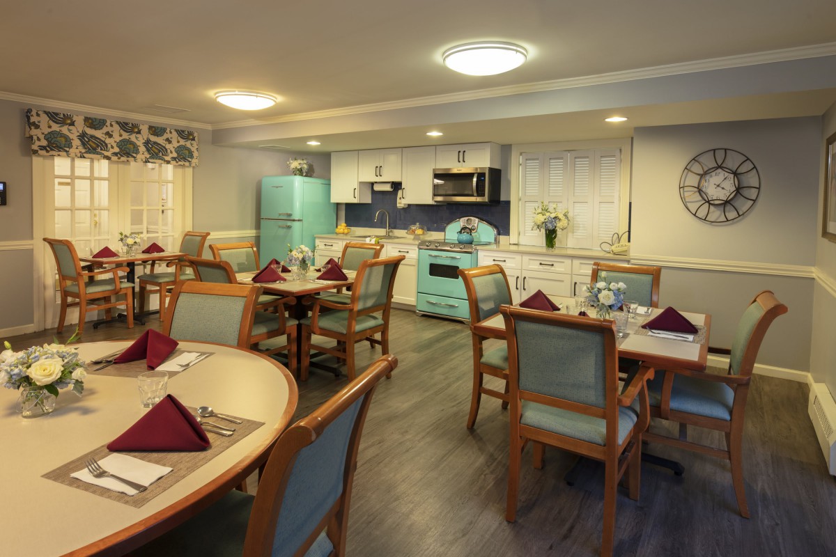A well-decorated dining room with retro-style kitchen appliances and neatly arranged tables and chairs.