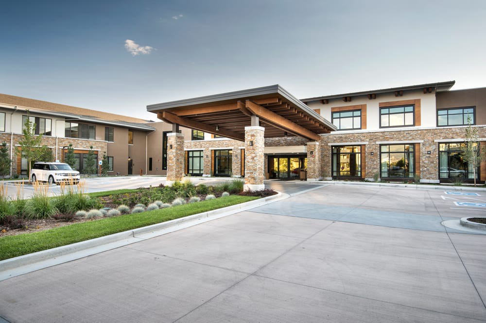A modern building with a prominent entrance featuring wooden beams and glass windows.