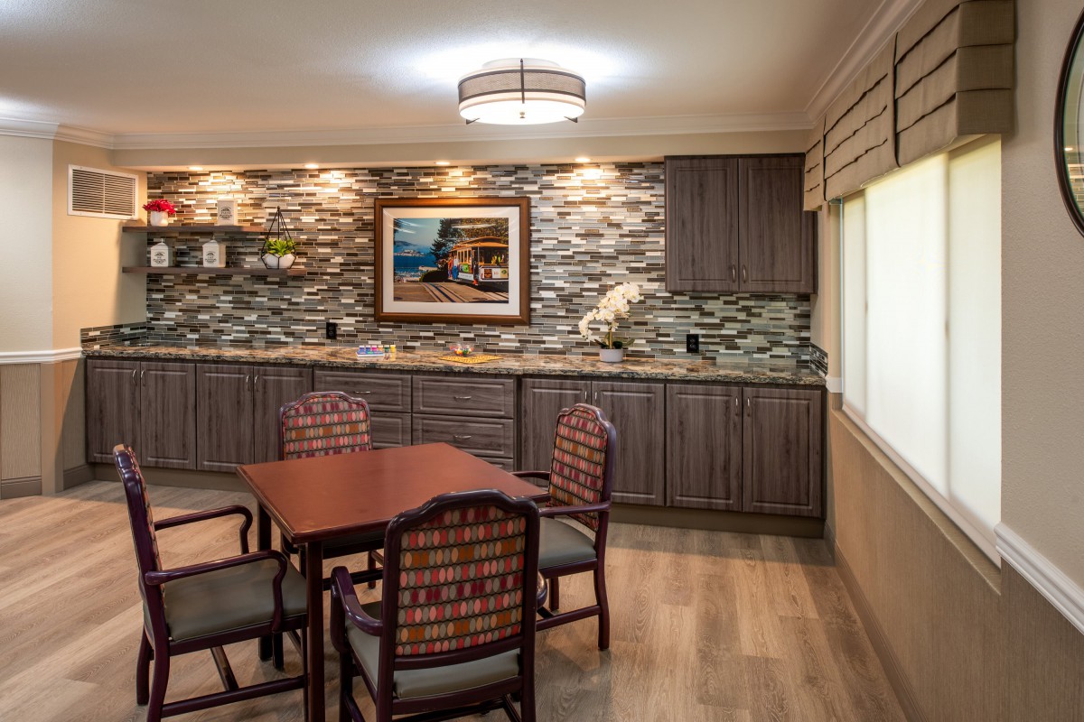 A modern dining room with a stylish table and chairs set, featuring a stone accent wall, artwork, and ambient lighting.