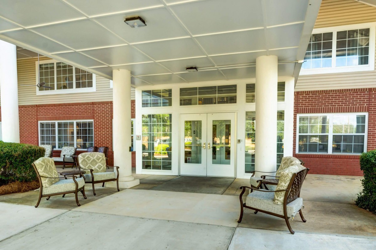 A covered entrance with seating and columns leading to a building's doors.