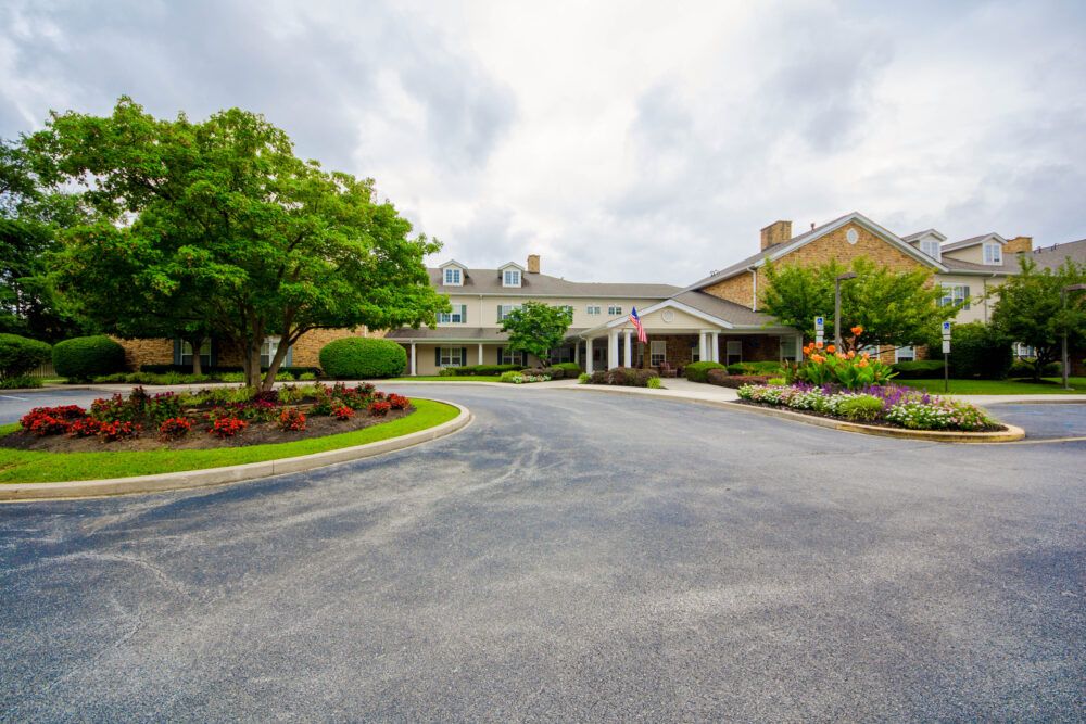 A scenic view of a building entrance surrounded by landscaped gardens and trees under a cloudy sky.
