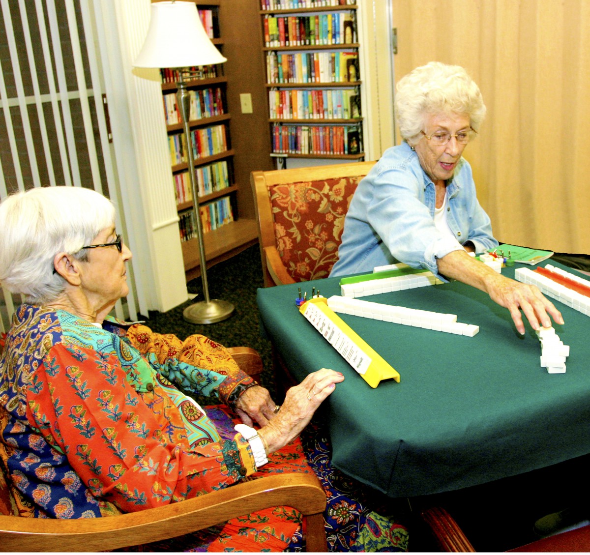 Two elderly women engaged in a game at a library.