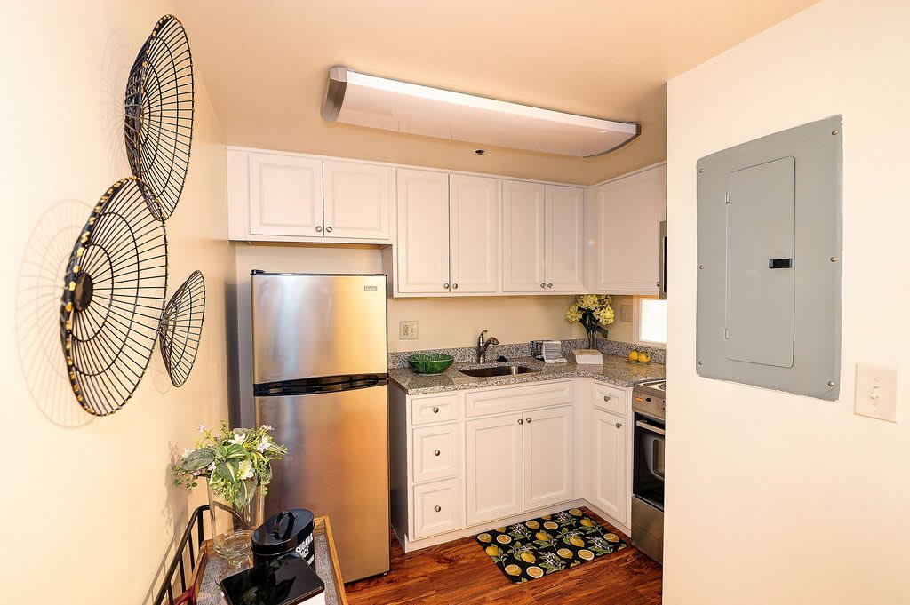 A compact kitchen with white cabinets and stainless steel appliances.