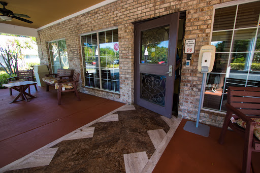 A welcoming entrance featuring a door, brick walls, and a comfortable bench.