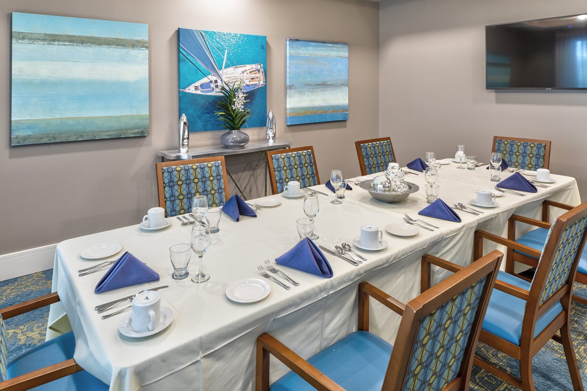 A beautifully arranged dining area with a table set for a formal meal, featuring blue napkins and elegant artwork on the walls.