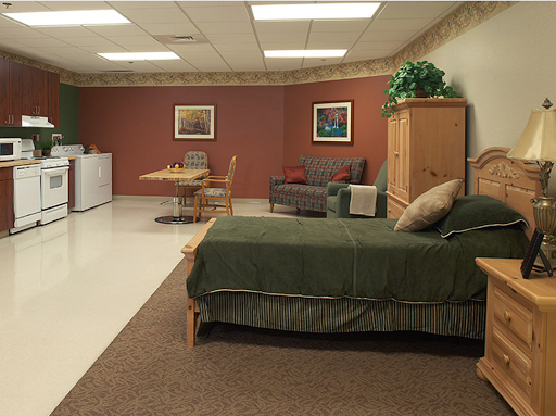 A cozy living space featuring a bed, sofa, dining table with chairs, and a refrigerator.