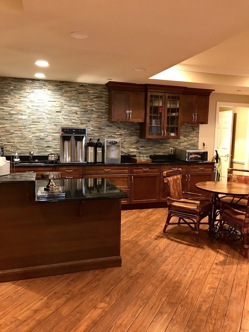 A cozy kitchen area featuring wood cabinets and a stone backsplash, complete with a dining table and modern lighting.