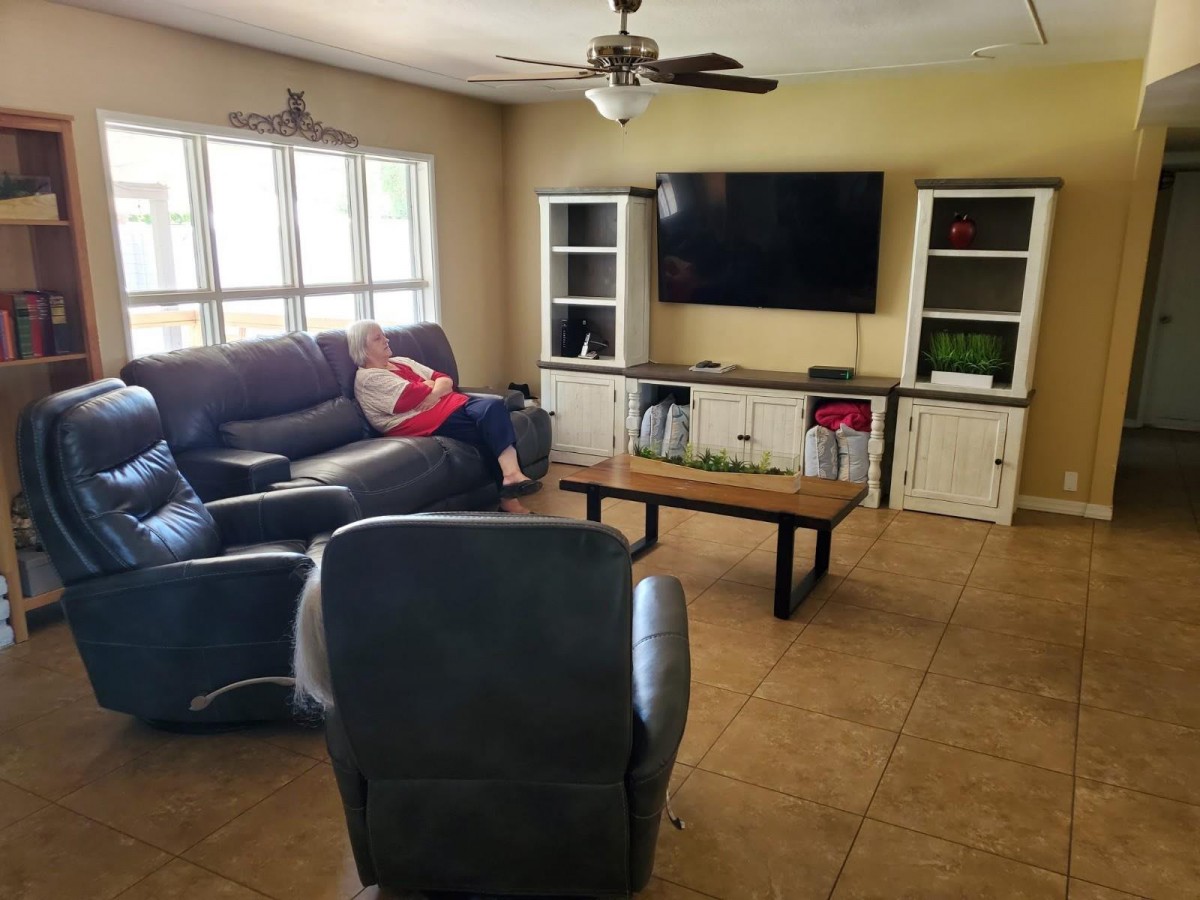 A cozy living room with a sofa, television, and a coffee table. A person is lounging on the sofa.