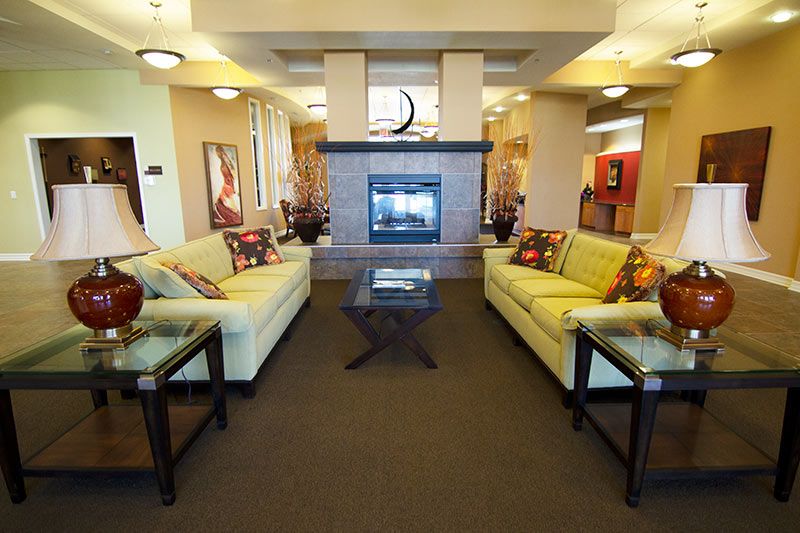 A modern living room with a central fireplace, surrounded by sofas and accent lighting.