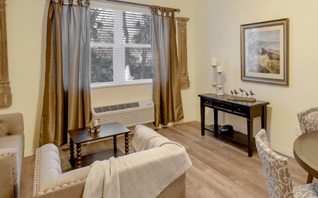 A cozy living room with neutral tones, featuring a comfortable sofa, wooden coffee table, and elegant curtains.