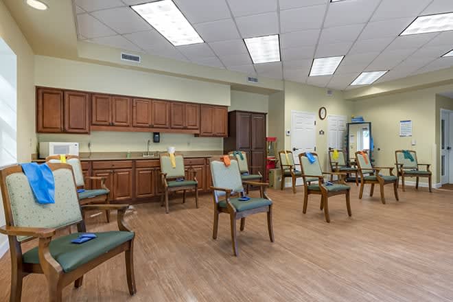 An empty waiting room with neatly arranged chairs and a wooden floor, typical of a medical facility.