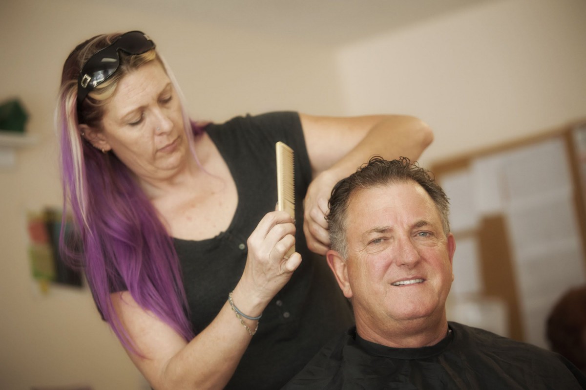 A hairdresser gives a man a haircut at a salon.