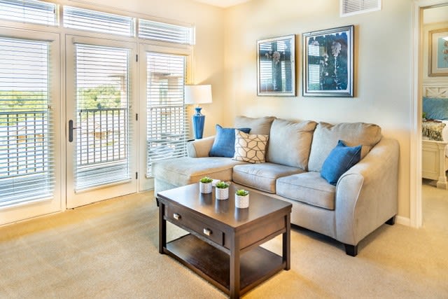 A cozy living room with a beige sofa and blue cushions, featuring a wooden coffee table and elegant decor.