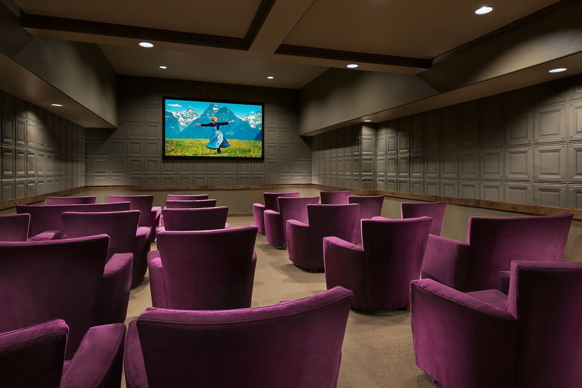 A cozy home theater with purple chairs and a large screen.