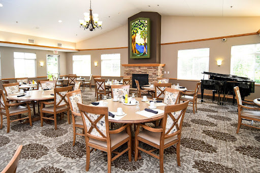 A cozy dining area featuring wooden tables and chairs, adorned with a beautiful stained glass window, perfect for meals and gatherings.