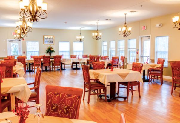 A spacious and elegantly decorated dining room with multiple tables and chandeliers.