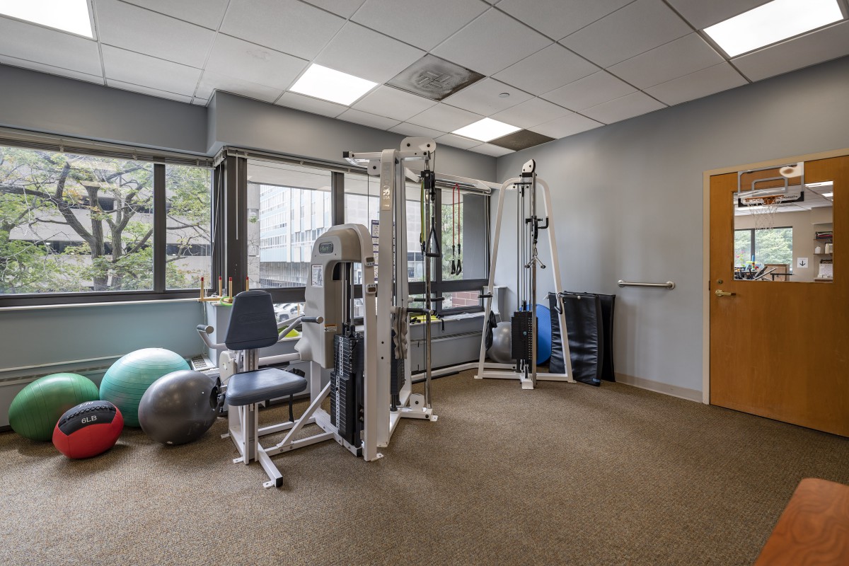 A well-lit gym with various exercise equipment, including weight machines and stability balls.
