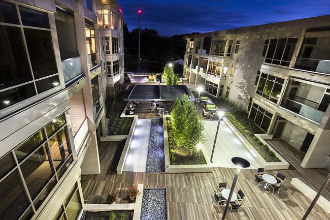 Modern apartment complex courtyard illuminated at night.
