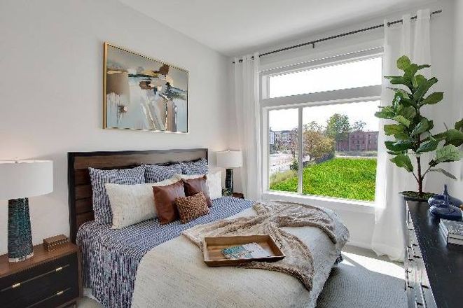 A cozy bedroom with stylish decor and large window allowing natural light.