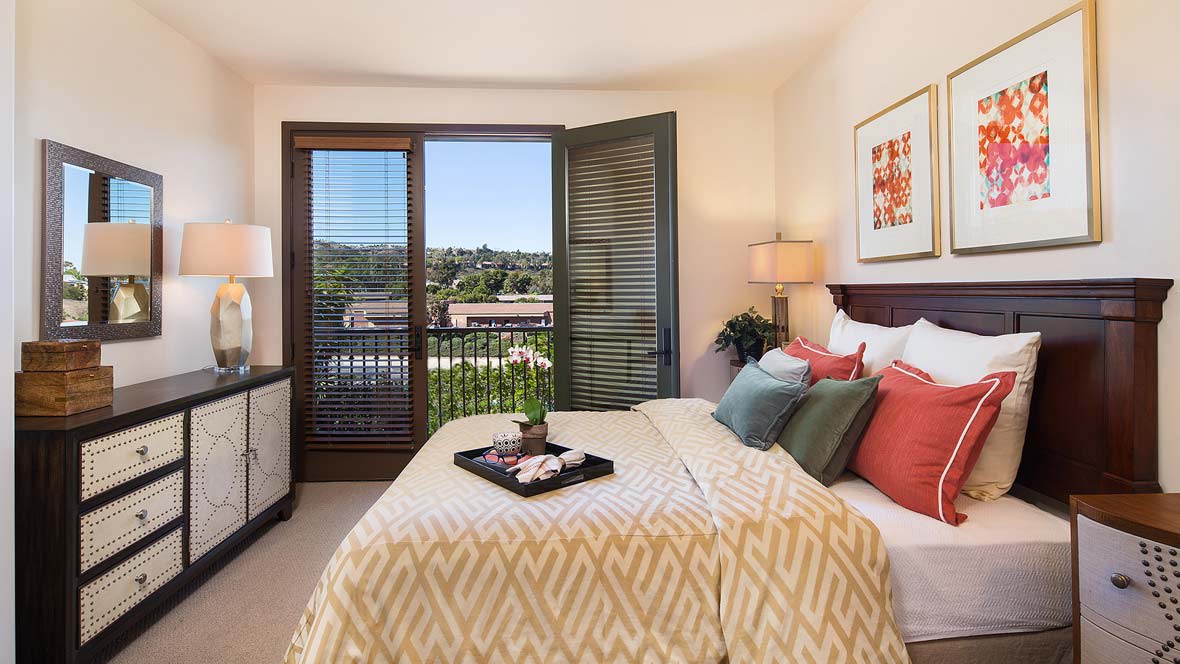 A cozy bedroom with modern decor and a view of the outdoors from a balcony.
