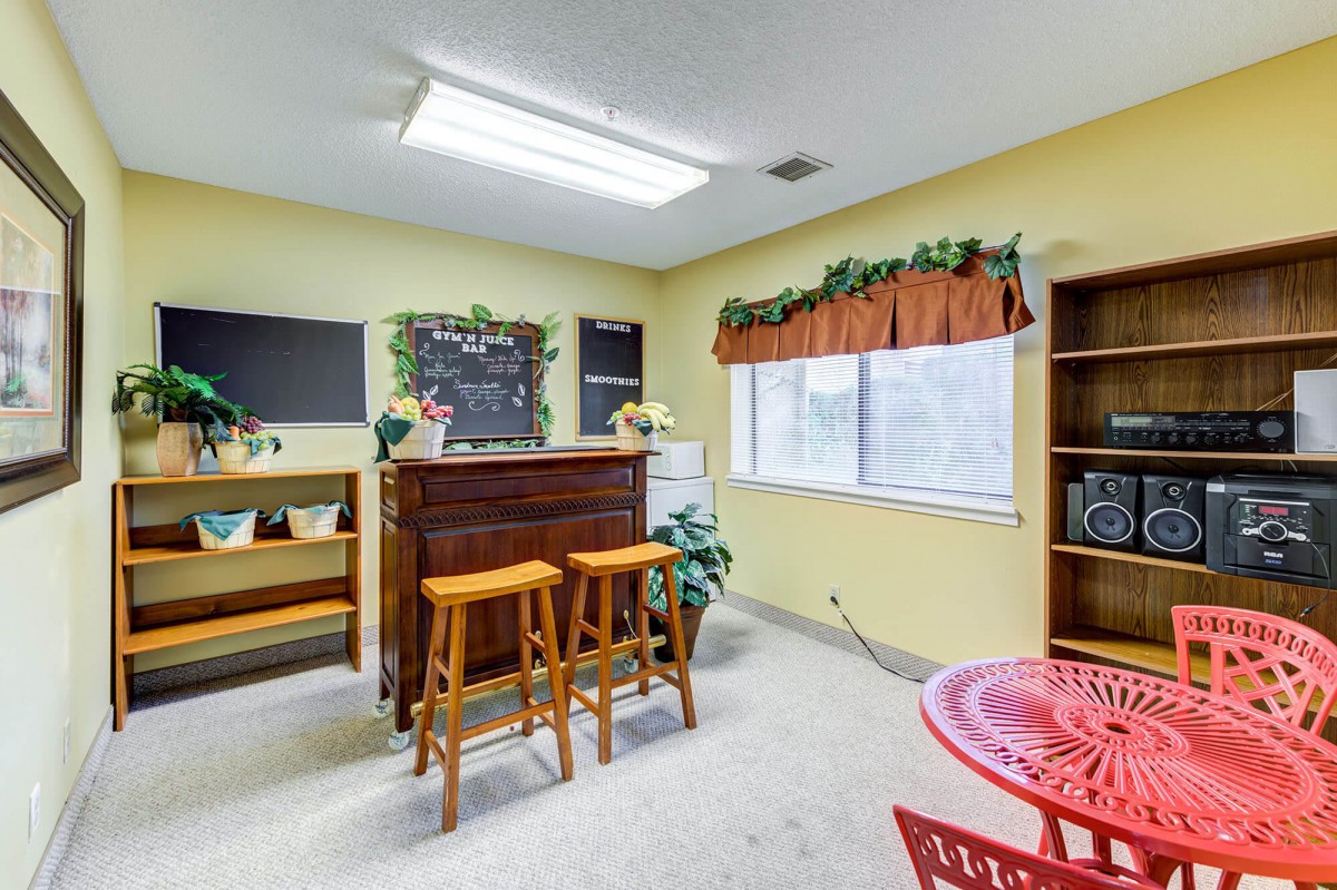 A cozy indoor bar area with stools, decorated with plants and a chalkboard menu.