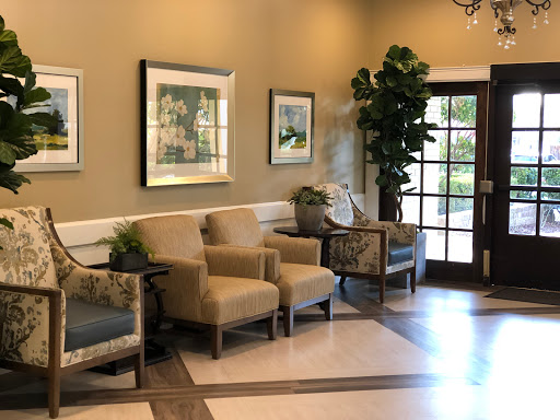 A cozy waiting area featuring comfortable chairs, decorative artwork, and indoor plants.