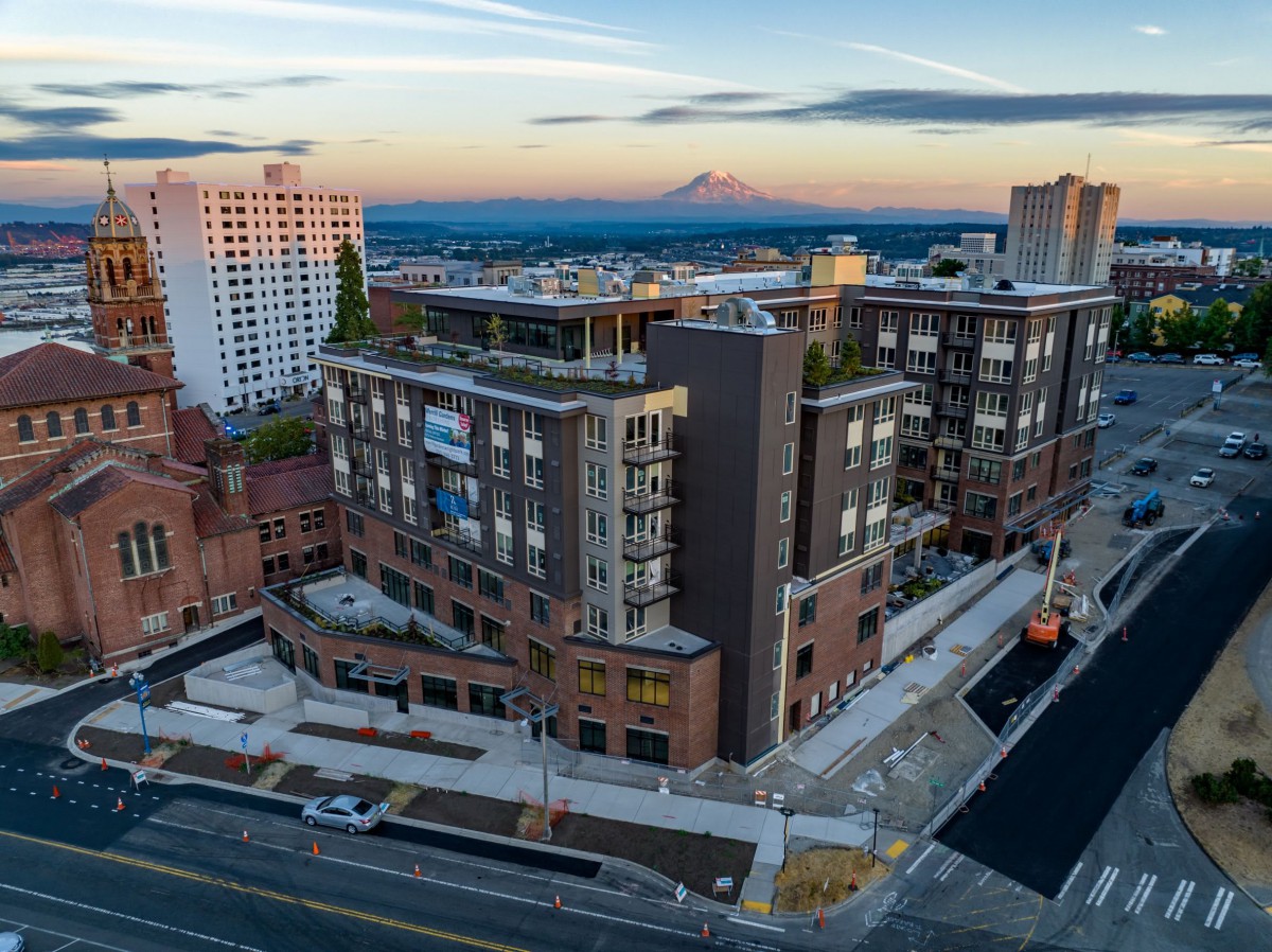 Aerial view of a modern urban area with buildings and streets at sunset, with a mountain in the background.
