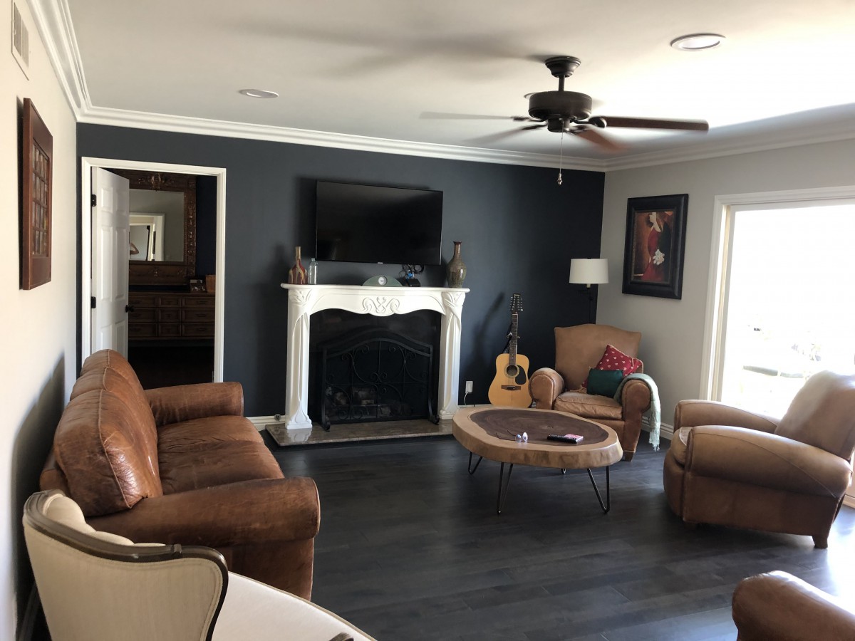 A modern living room featuring a large sofa, fireplace, wall-mounted television, and a guitar in the corner.