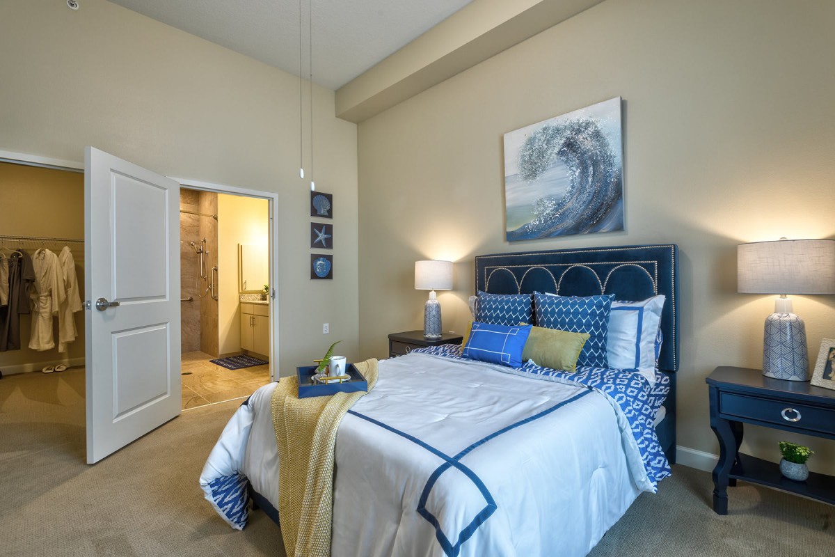 A modern bedroom featuring a blue and beige color scheme with stylish decor and artwork.