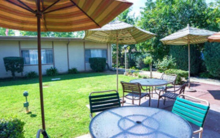 A sunny outdoor patio area with tables, chairs, and umbrellas.