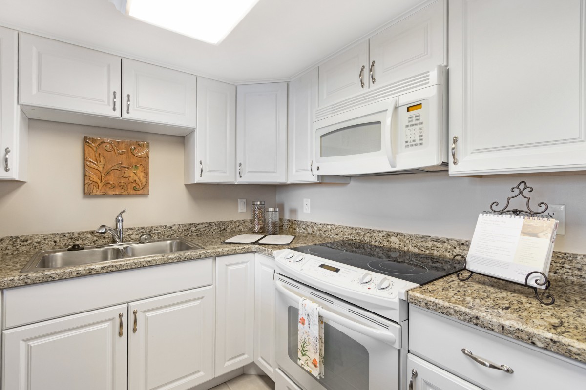 A modern kitchen with white cabinets and granite countertops.