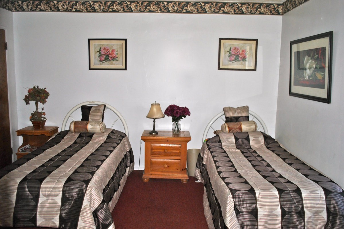 A bedroom with two single beds and a nightstand in between, decorated with striped bedding and wall art.