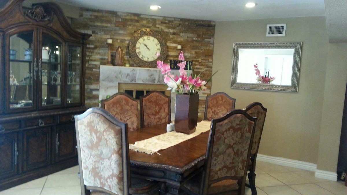 Elegant dining room with a wooden table set, fireplace, and floral centerpiece.