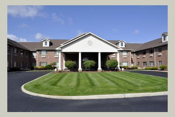 A well-maintained hotel exterior with a green lawn and clear blue sky.