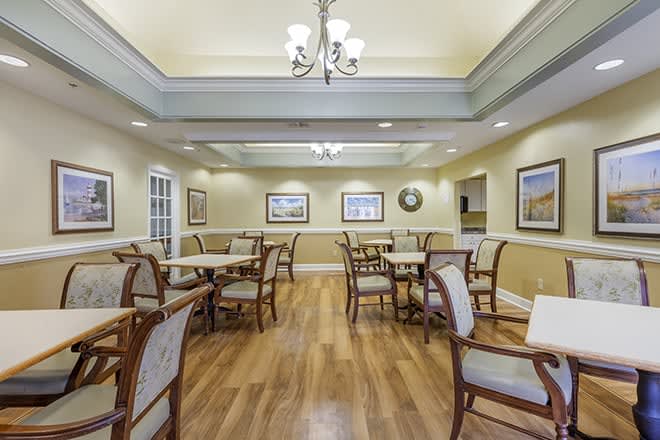 A well-lit dining area with wooden floors and elegant seating arrangements.