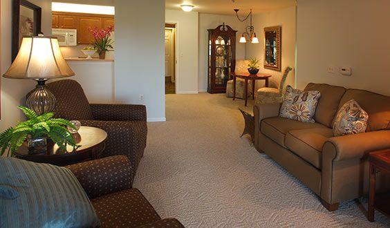 A cozy living room interior with sofas, an armchair, and warm lighting.