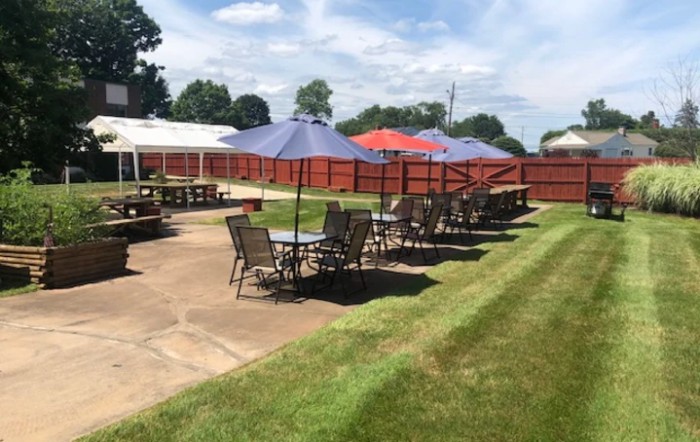 An outdoor patio area with tables and umbrellas on a sunny day.