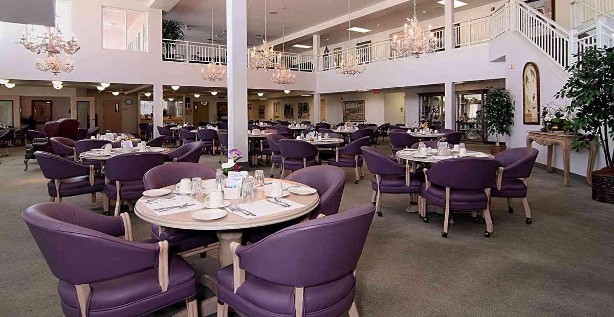 A spacious and elegantly decorated restaurant dining area with purple chairs and chandeliers.