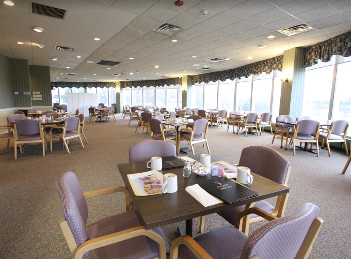 An empty restaurant dining area with neatly arranged tables and chairs, featuring large windows.