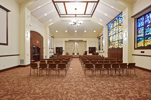 A serene interior view of a chapel featuring rows of chairs and a beautiful stained glass window.