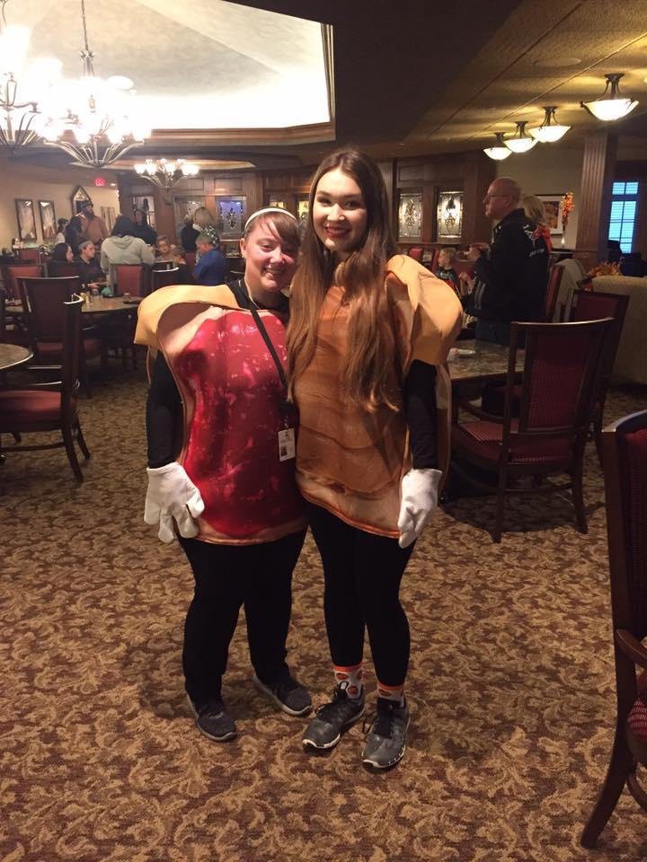 Two people wearing food-themed costumes pose in a restaurant.