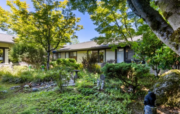 A serene residential home surrounded by lush greenery and trees.