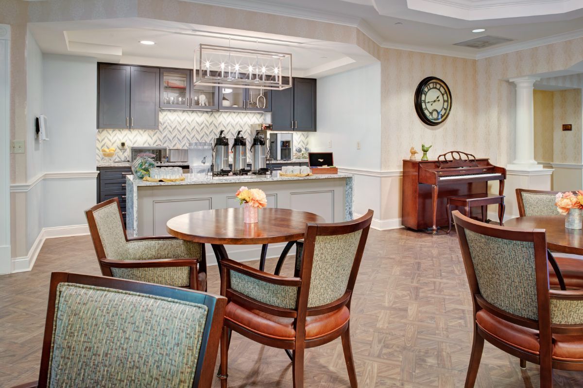 A cozy cafe interior with tables and a kitchenette featuring a coffee station.