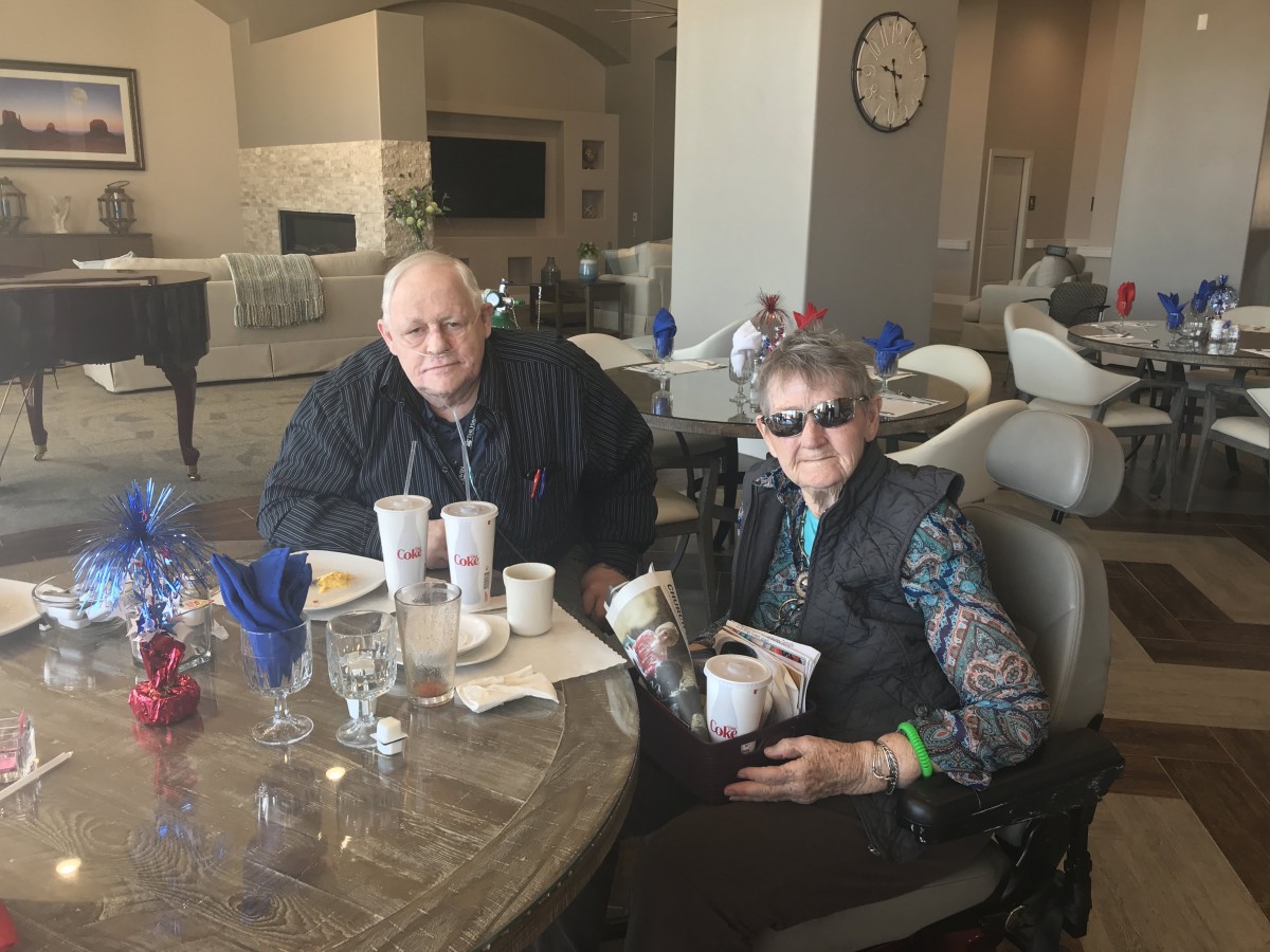 An elderly couple enjoying a meal together at a dining table in a cozy indoor setting.