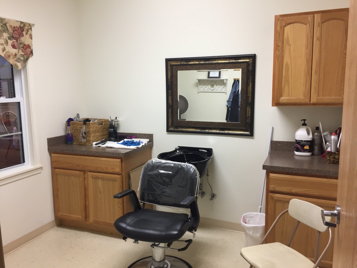 A barber shop interior with a chair, mirror, and cabinets.