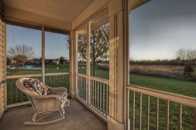 A tranquil screened porch with comfortable seating offering a peaceful view of the natural surroundings during the evening.