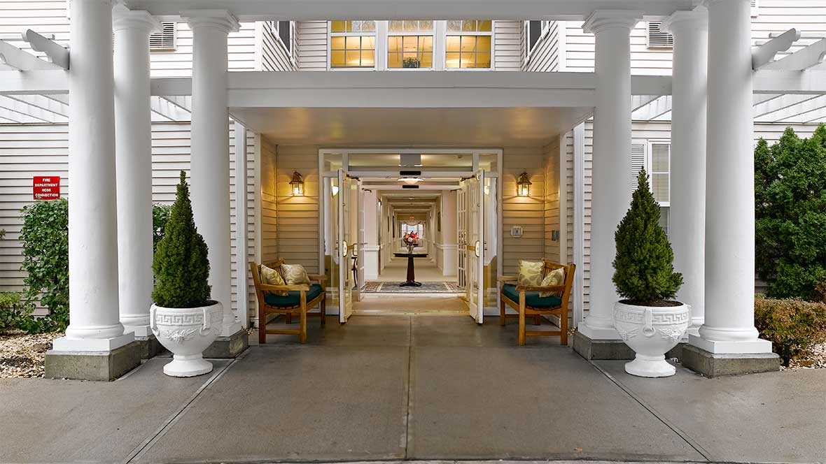 Elegant building entrance with pillars and seating area.
